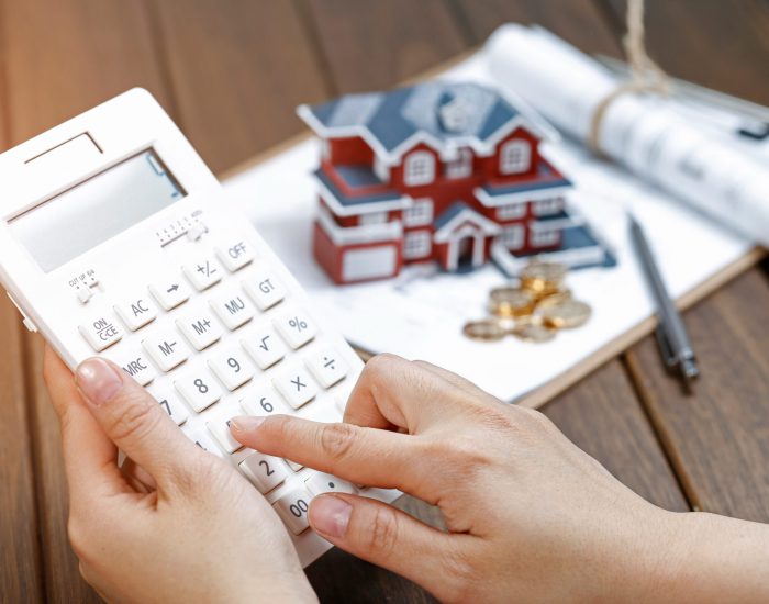 A female hand operating a calculator in front of a Villa house model